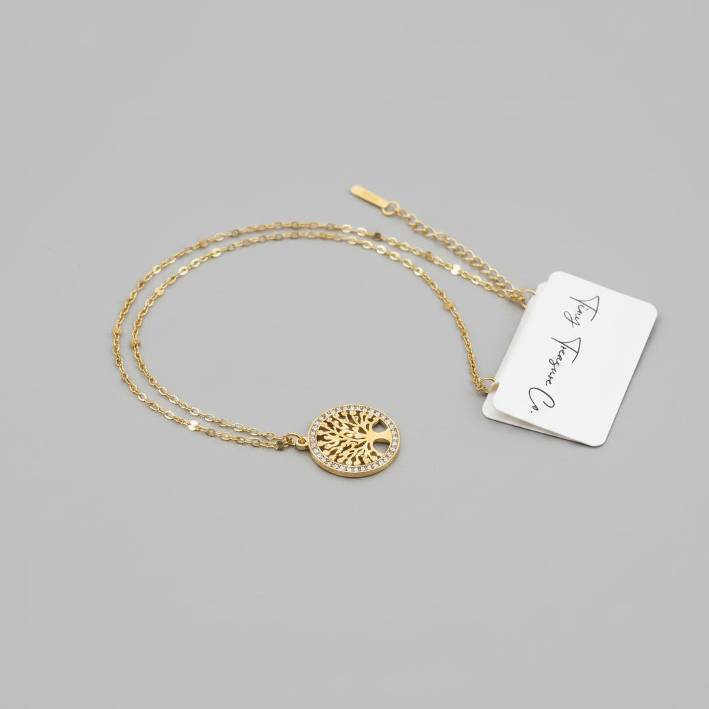 Gold necklace with a circular pendant on a gray surface, accompanied by a tag.