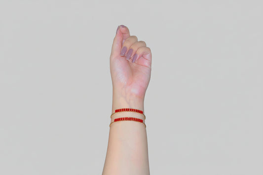Hand with red bracelet on wrist against a reflective surface