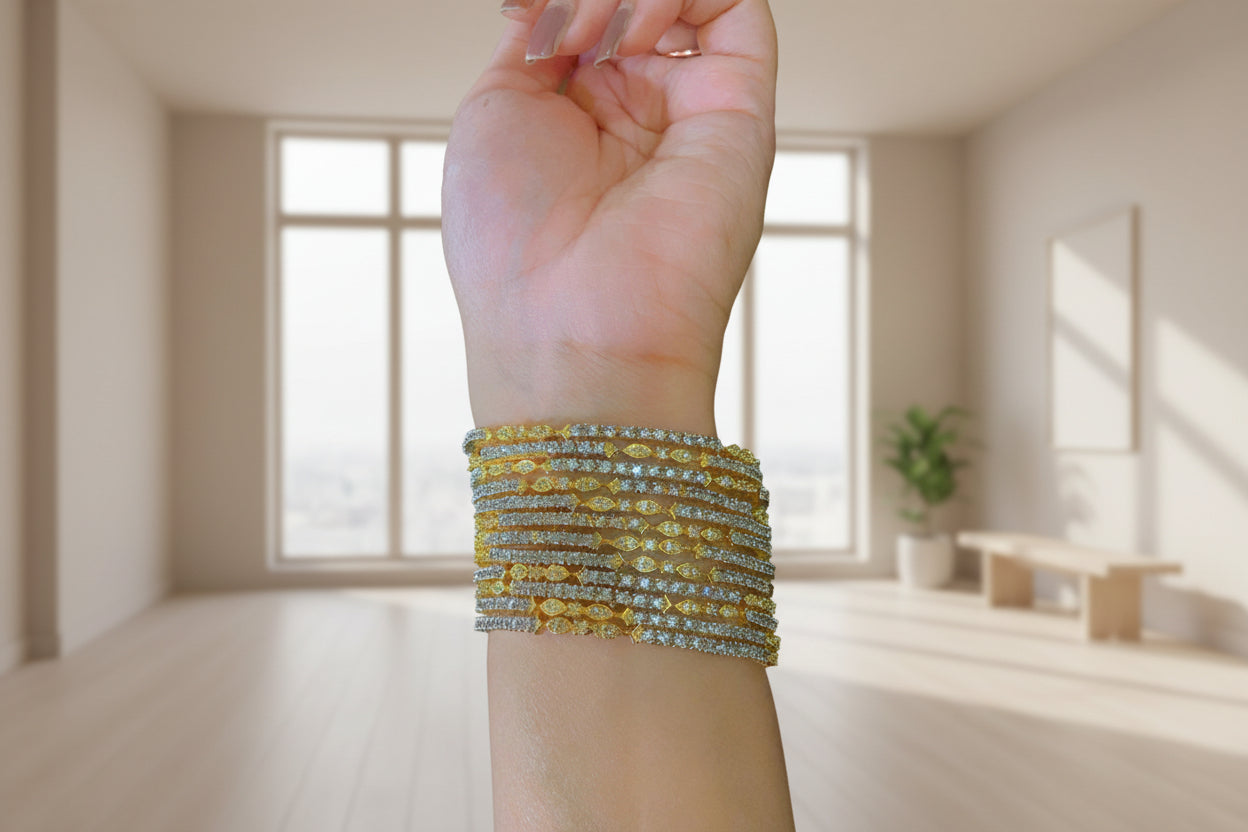 Hand wearing multiple gold and diamond bracelets on a blurred background