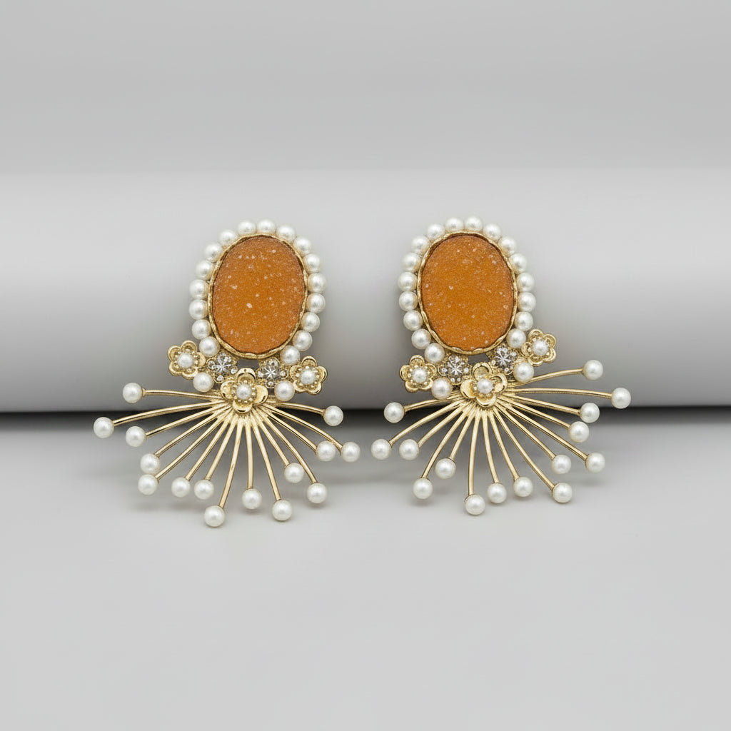 Ornate earrings with pearls held against a blurred background