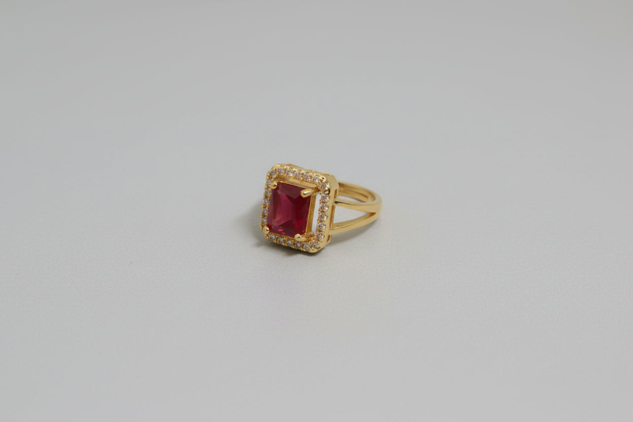 Gold ring with a red gemstone on a blue surface