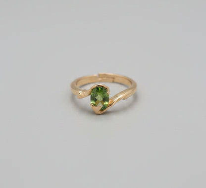 Gold ring with a green gemstone on a reflective surface