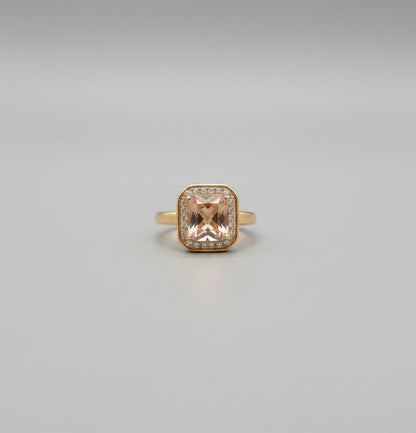 Gold ring with a large orange gemstone on a reflective surface
