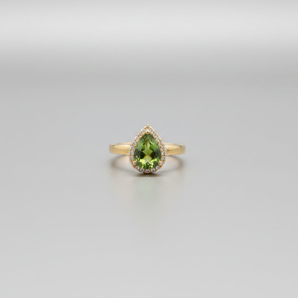 Gold ring with green gemstones on a reflective surface