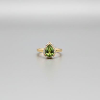 Gold ring with green gemstones on a reflective surface
