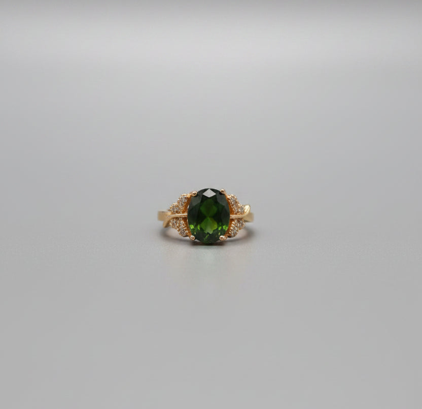Gold ring with a green gemstone on a desk in an office setting