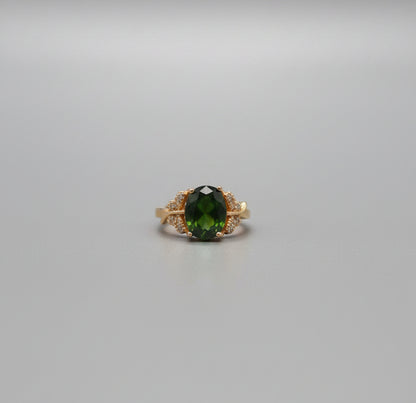 Gold ring with a green gemstone on a desk in an office setting