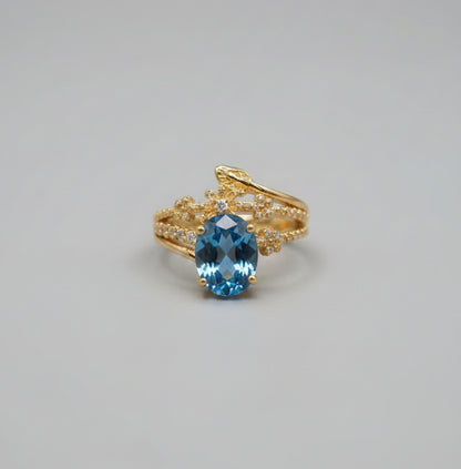 Gold ring with a blue gemstone on a reflective surface