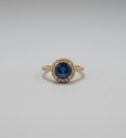 Gold ring with a blue gemstone on a reflective surface