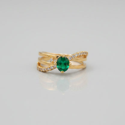 Gold ring with a green gemstone on a reflective surface