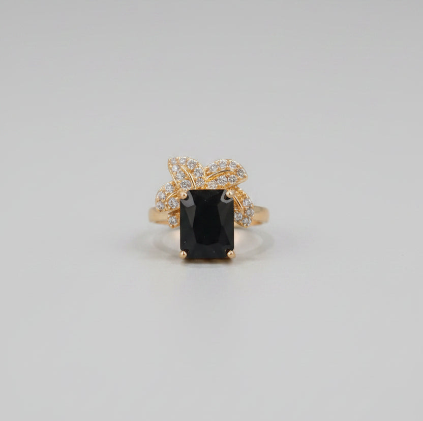 Gold ring with a black gemstone on a reflective surface