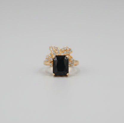 Gold ring with a black gemstone on a reflective surface