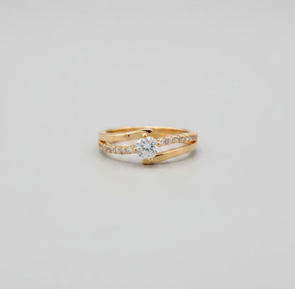 Gold ring with a clear gemstone on a reflective surface, blurred background