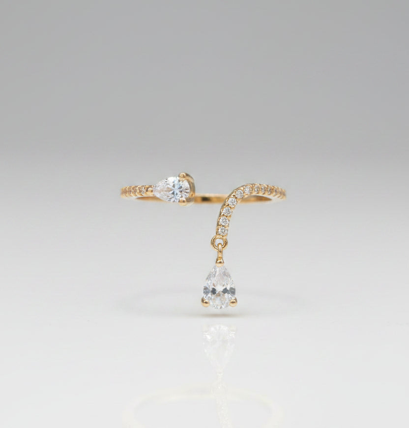 Gold ring with a teardrop-shaped gemstone on a black surface