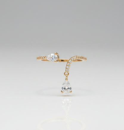 Gold ring with a teardrop-shaped gemstone on a black surface