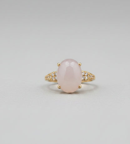 Gold ring with a large central stone on a reflective surface