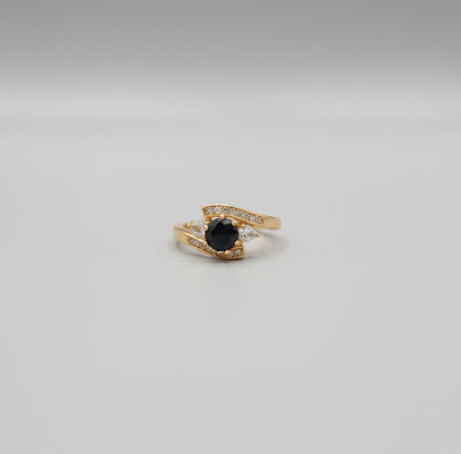 Gold ring with a black gemstone on a reflective surface