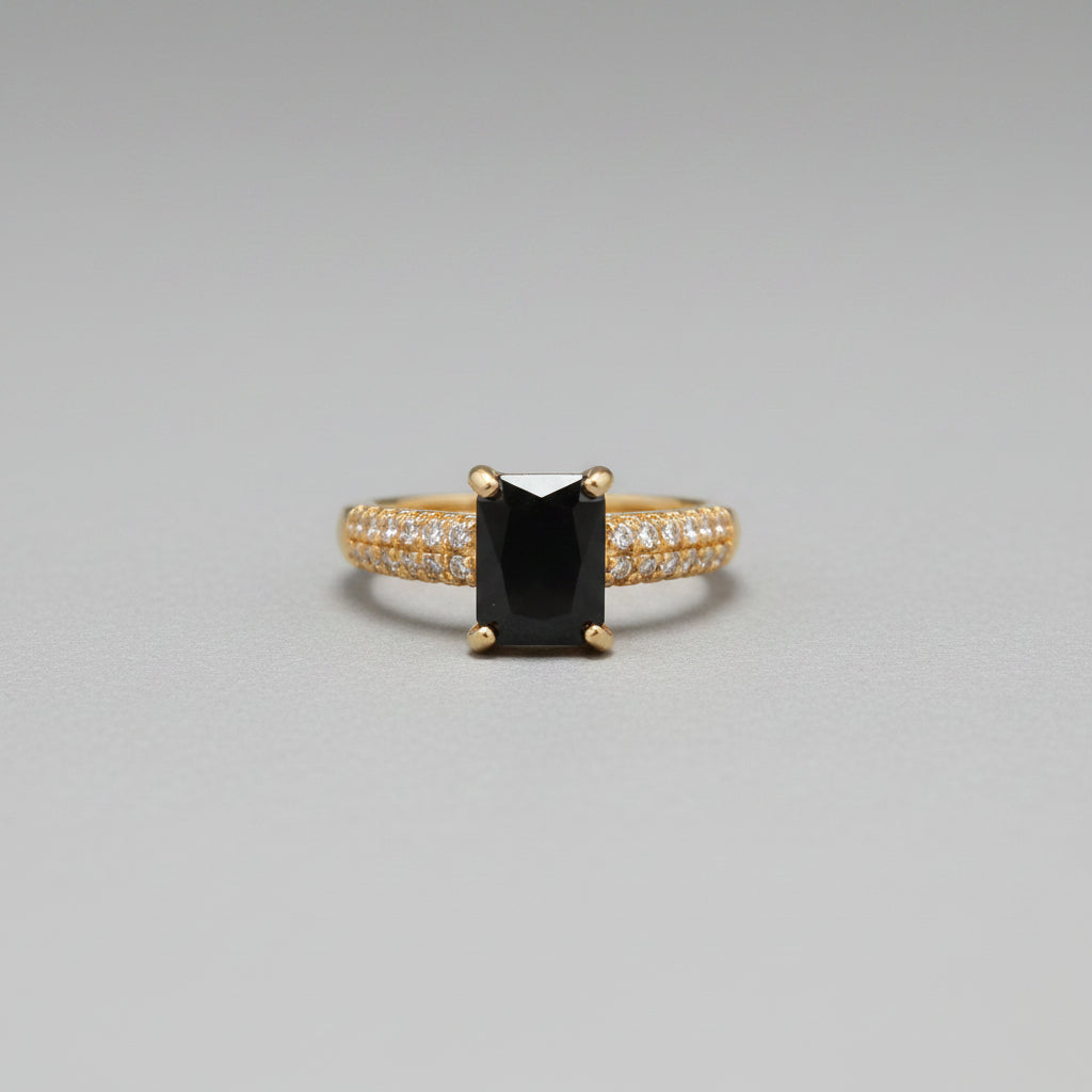 Gold ring with a black gemstone on a reflective surface