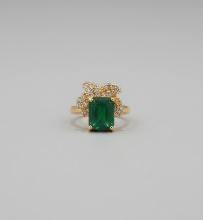 Gold ring with a green gemstone on a reflective surface