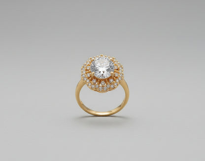 Gold ring with a large central gemstone on a reflective surface