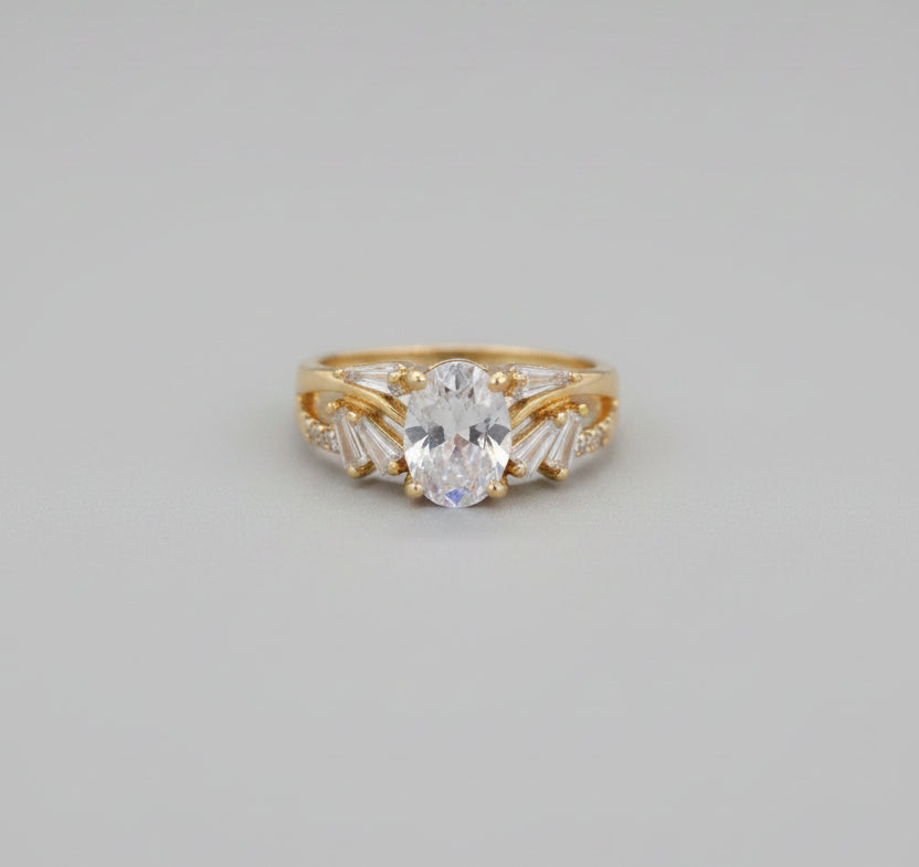 Gold ring with a large central stone on a reflective surface
