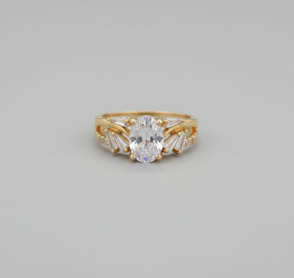 Gold ring with a large central stone on a reflective surface
