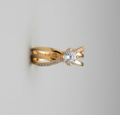 Gold bow-shaped ring with a diamond on a reflective surface