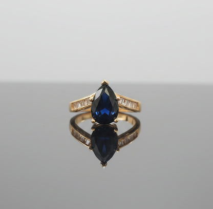 Gold ring with a black gemstone on a reflective surface