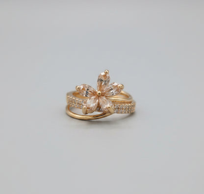 Gold ring with butterfly design on a reflective surface