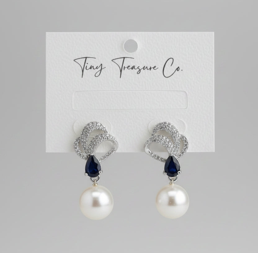 Pearl earrings with black gemstones on a Tiny Treasure Co. card.