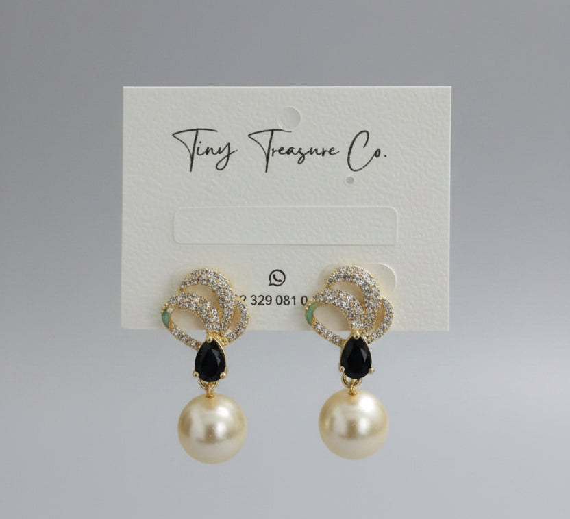 Gold earrings with black accents and pearl-like beads on a 'Tiny Treasure Co.' card.