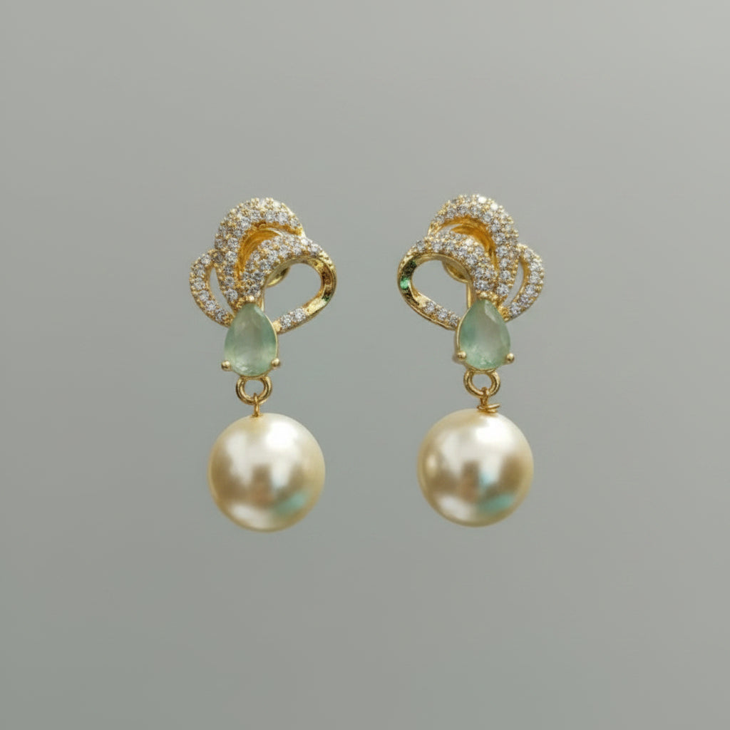 Gold and pearl earrings on a 'Tiny Treasure Co.' card held by a hand.