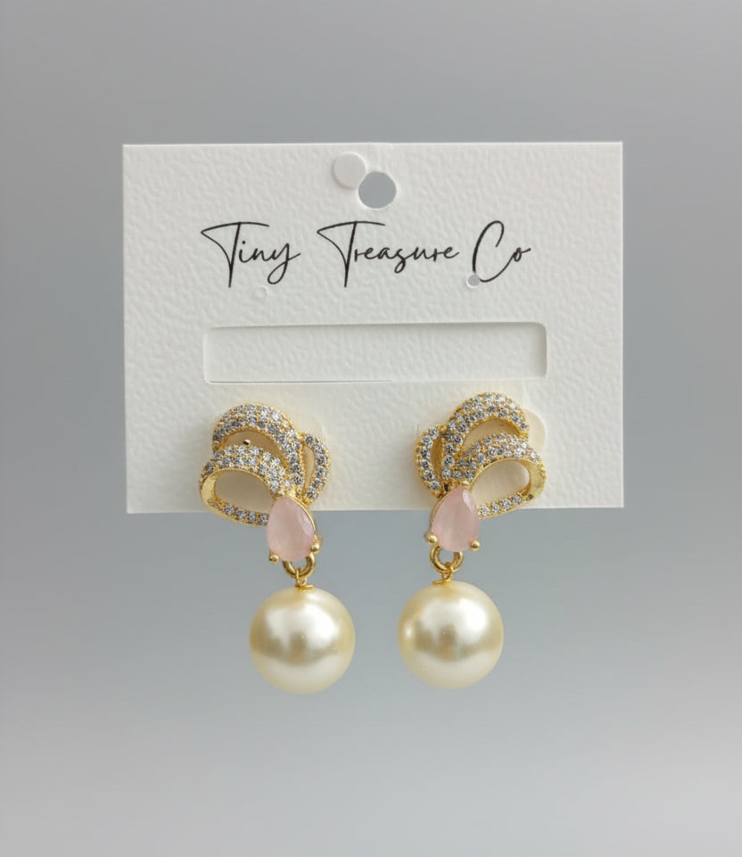 Gold and pearl earrings on a Tiny Treasure Co card held by a hand.