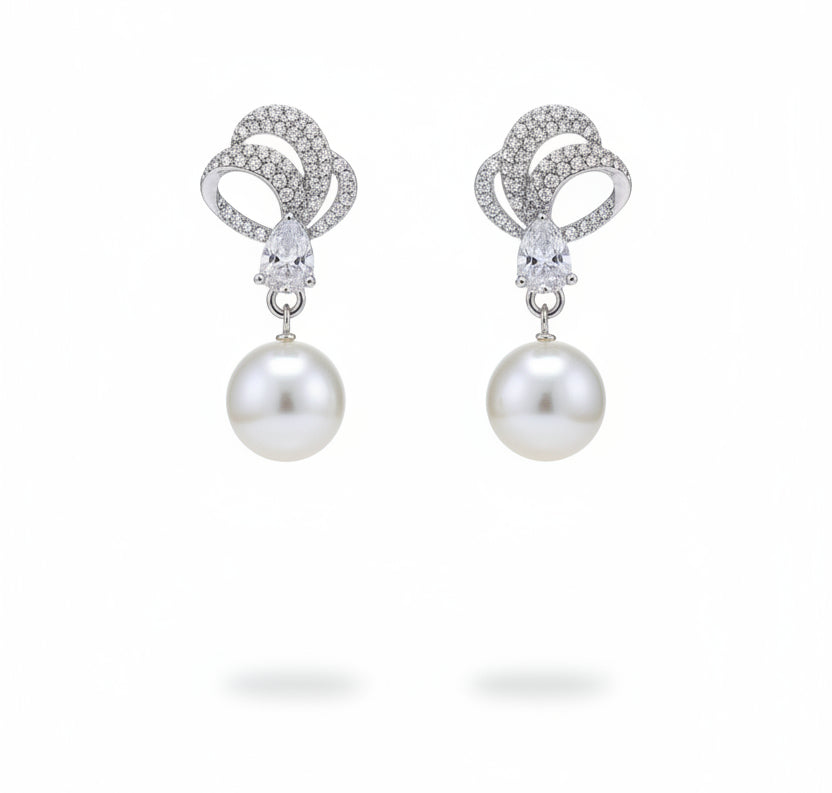 Pearl earrings with silver designs on a Tiny Treasure Co. card.