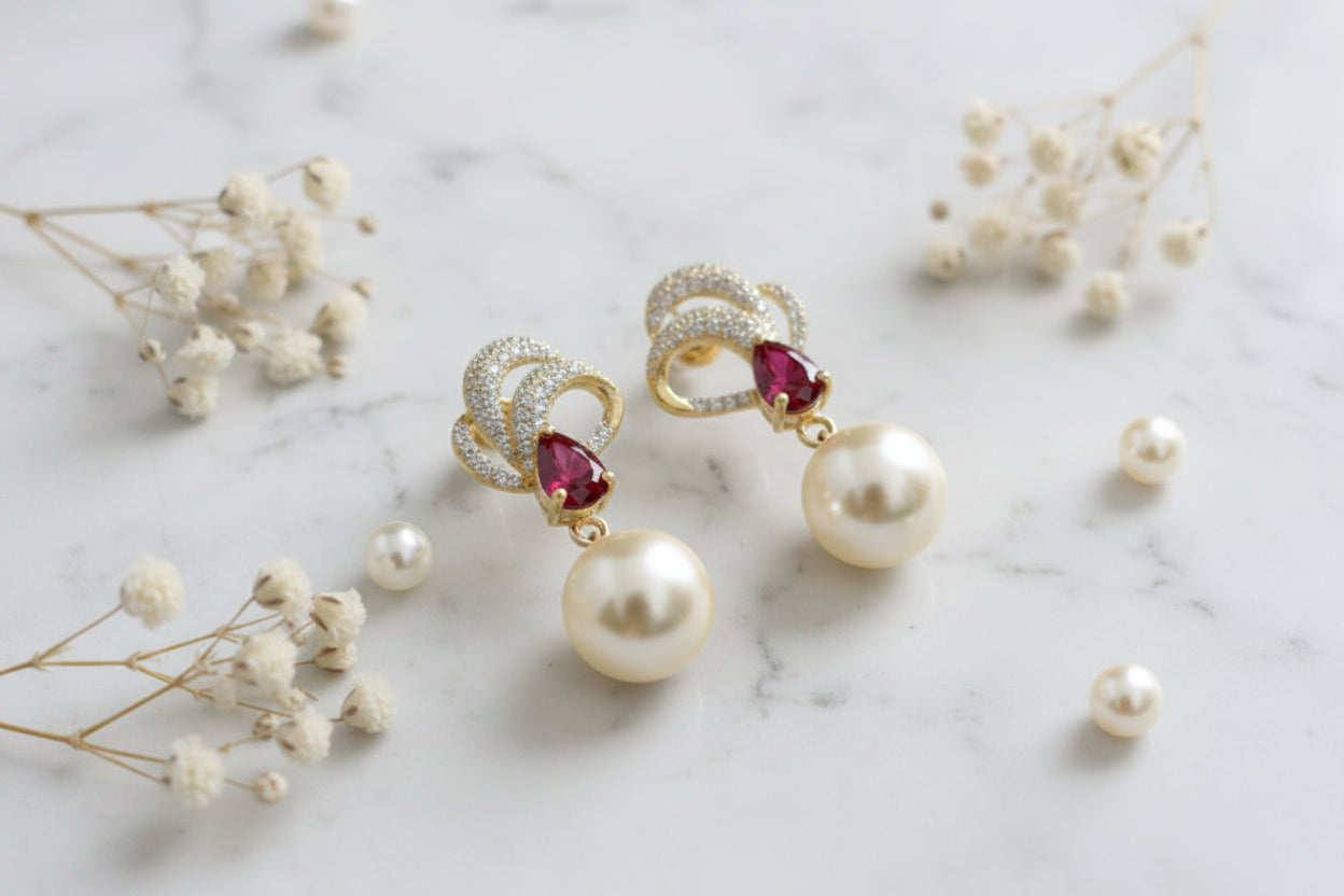 Gold earrings with pearls and red stones on a 'Tiny Treasure Co.' card.