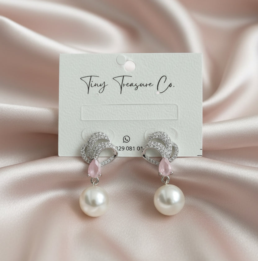 Earrings on a 'Tiny Treasure Co.' card held by a hand.