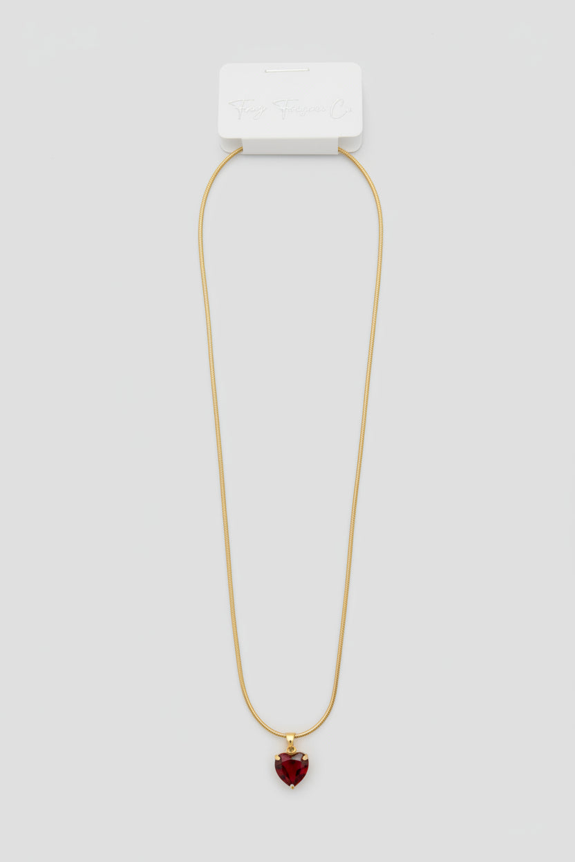 Necklace with a white rectangular pendant and red gemstone on a gray fabric background