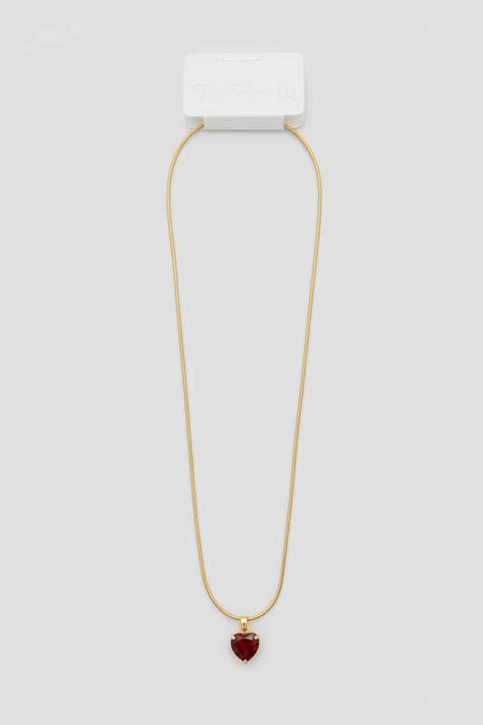 Necklace with a white rectangular pendant and red gemstone on a gray fabric background