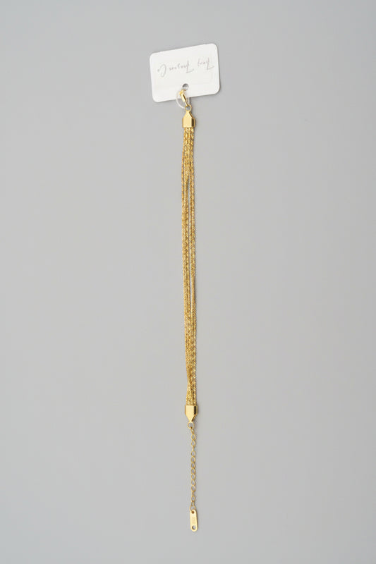 Gold bracelet on a gray surface with a white label