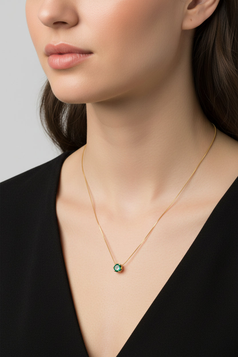 Gold necklace with a green gemstone on a beige background