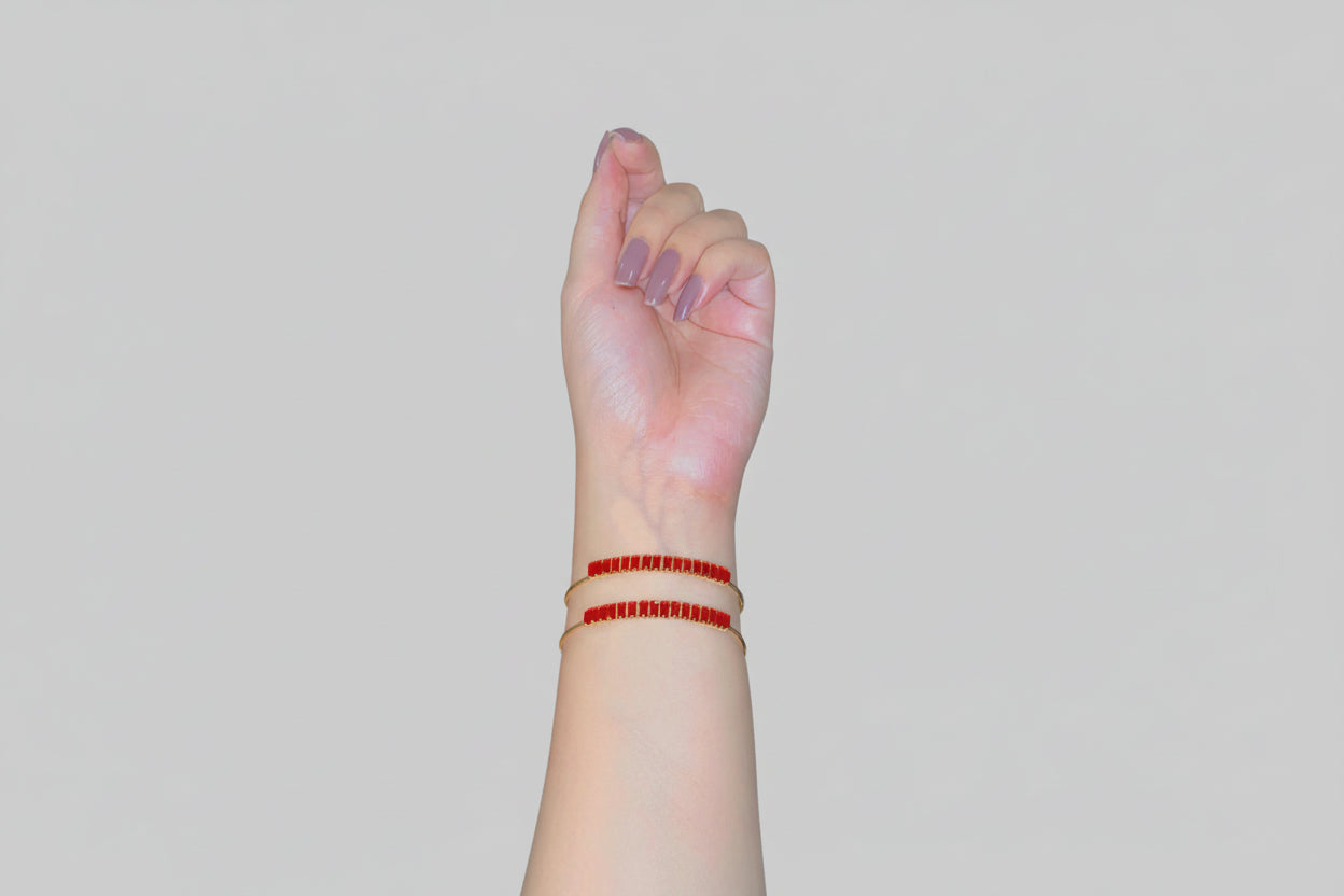 Hand with red bracelet on wrist against a reflective surface