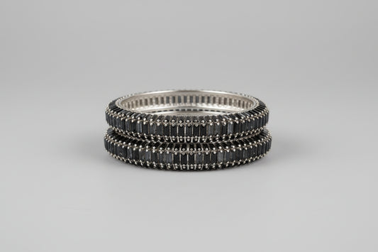 Stack of silver and black bangles on a gray background